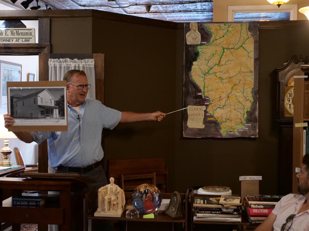 Presenter pointing at a map of Lincoln's Illinois circuit, framed photo in hand